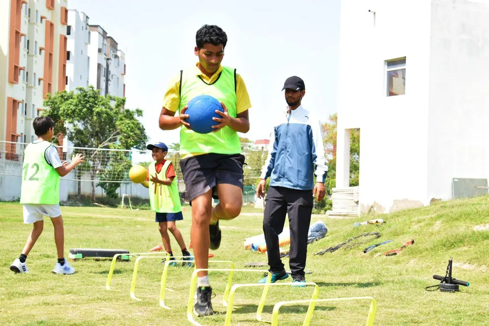 PLAY n FIT junior stepping through an agility hurdle while carrying a medicine ball