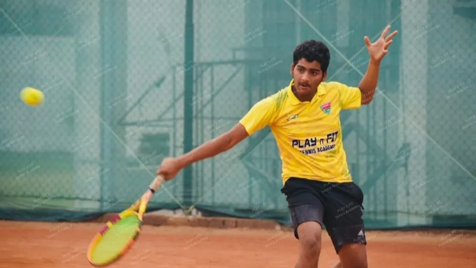PLAY n FIT player in the yellow academy jersey stretching wide for a forehand on a clay court